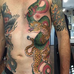 The snake seems to be winning in this intense side tattoo by Ben Siebert (IG—bensiebert). #BenSiebert #bold #colorful #leopard #snake #traditional