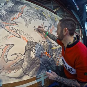 Action shot of Crez Adrenalink getting busy on this impressive Dragon mural. Photo by Jessica Paige for Tattoodo. #art #londontattooconvention #dragon #mural