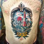Beautiful and classic looking scenic tattoo with a lighthouse. Awesome work by Tom Lortie. #TomLortie #traditionaltattoo #coloredtattoo #lighthouse #scenic #stomachtattoo