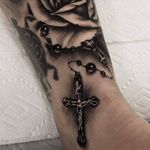 A black and grey Rosary next to a rose by Kevin Fleming (IG—kevinflemingtattoo).