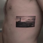 Lighthouse tattoo by Fillipe Pacheco #fillipepacheco #landscapetattoo #blackandgrey #realism #realistic #hyperrealism #landscape #ocean #mountain #building #lighthouse #sky #clouds #architecture