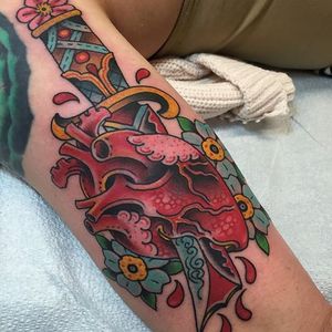 Beau Brady brings the edge in this awesome take on the timeless heart and dagger tattoo. #banger #BeauBrady #bold #dagger #heart #AmericanTraditional #flowers