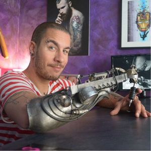 JC Sheitan poses with his prosthetic arm customized by sculptor Gonzal #JCSheitan #prostheticarm #tattooartist #Gonzal #amputee #tattoomachine