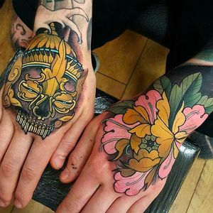 Clean and solid looking hand tattoos of a Peony or king flower and a Tibetan skull. #ElliottWells #handtattoo #skull #peony #oriental