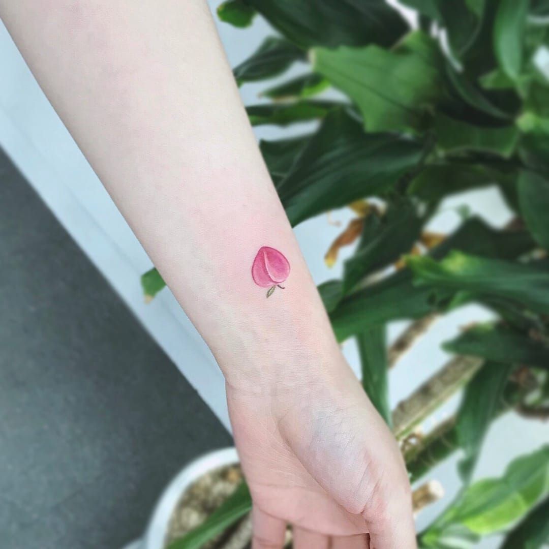 Tiny peach tattoo located on the bicep minimalistic