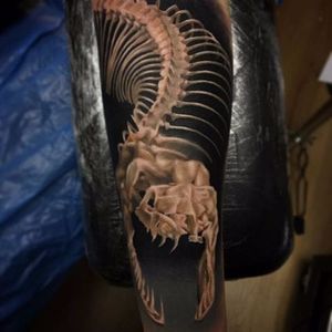 An alternative snake tattoo and looks killer against black by Vid Blanco. #VidBlanco #photorealism #realism #UKtattooer #minimalpalette #blackandgrey #snake #skeleton