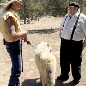 A photo of George R. R. Martin with a handler at a wolf sanctuary.