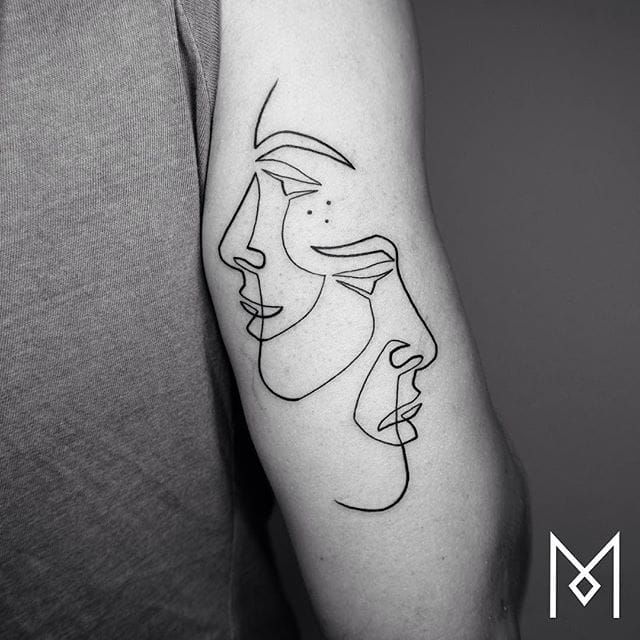 Minimalist face tattoo on the inner forearm
