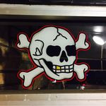A skull and crossbones painted by Tina Fino on Bound for Glory's window (IG—tina_fino). #BoundforGlory #signpainting #tattooinspired #skullandcrossbones #TinaFino