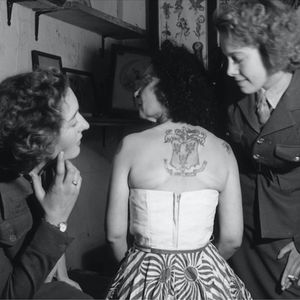 A photo of two service women admiring an older Jesse Knight's back tattoo. #firstfemaletattooist #GreatBritain #history #JesseKnight #tattoopioneer