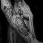 Mary tattoo by Chuey Quintanar #ChueyQuintanar #religioustattoo #blackandgrey #realism #realistic #oldschool #VirginMary #rose #flower #leaves #nature #prayer #light #filigree #stainedglass #Christian #Catholic #tattoooftheday