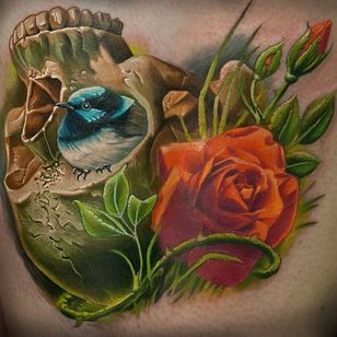 Un pajarito lindo y regordete metido en un cráneo vuelto hacia arriba.  Tatuaje de Frederick Bain #FrederickBain #realism #colorrealism #kranie #rose #bird