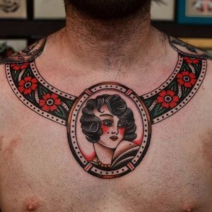 An awesome traditional collar tattoo with a lovely lady head broach by Florian Santus (IG—floriansantus). #collar #FlorianSantus #flowers #ladyheads #traditional