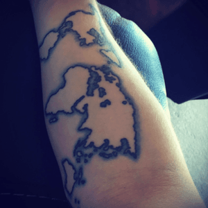 World tattoo on my inside right arm. Black outline with coastline done in blue UV ink. 