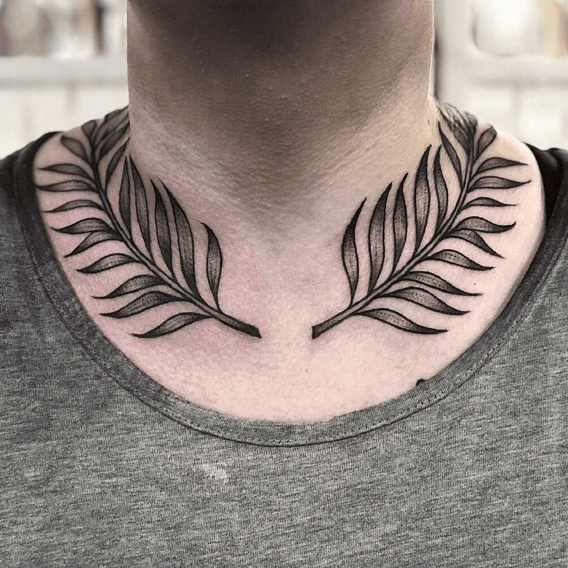 Fern leaf tattoo on the left side of the neck behind