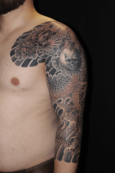 Stunning blackwork chest tattoo by Stewart Robson featuring a fierce dragon and skull design in traditional Japanese style.