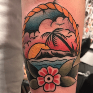 Vibrant traditional forearm tattoo featuring a sun, beach, tree, flower, and cloud design by talented artist Eddy Ospina