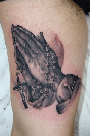 Stunning black and gray tattoo of praying hands on upper arm by Stewart Robson. A powerful symbol of faith and devotion.