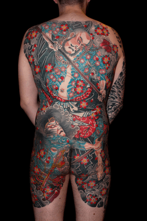 Experience the beauty and strength of Japanese culture with a stunning back tattoo featuring sakura flowers and a fierce samurai warrior, expertly done by Stewart Robson.