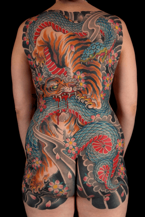 Stunning tattoo by Stewart Robson featuring a snake, tiger, and cherry blossoms in a traditional Japanese style.