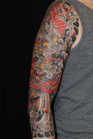 Beautiful Japanese style upper arm tattoo featuring a powerful dragon and delicate cherry blossom by Stewart Robson.