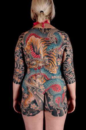 Immerse yourself in traditional Japanese tattoo art featuring a snake, tiger, and sakura motif. Perfect for a full body suit tattoo experience in London, GB.