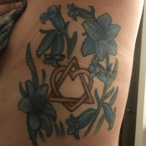 This is for my families. As a child of adoption, I'm so very grateful to know both families...birth and adopted. The middle symbol is the adoption system. The flowers are bluebells which is a sign of gratefulness. The flowers fully bloomed represent my adoptive and birth parents. The flower buds represent all of my birth siblings. 