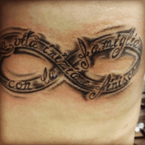 Infinity symbol on my left rib cage. It says "Life Begins and Ends with Family" in Italian