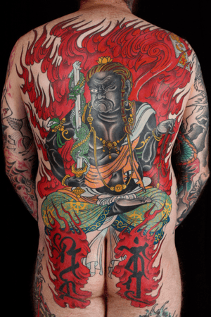 Incredible Japanese tattoo by Stewart Robson featuring a fierce dragon, sword, and fiery flames engulfing a man.