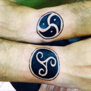 BDSM symbols tattooed on both upper wrists