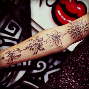 These four flowers represent my nuclear family members. By my wrist is the purple iris (which represents wisdom and spiritual guidance) for my dad. On my forearm is the arbor vitae fern (everlasting friendship) for my twin sister. In my 'elbow crease' is the sword lily (strength and courage) for my brother. On my bicep is the astor lily (patient love) for my mom. I designed and drew this, and Kenny Fajardo (Phoenix, AZ) tattoed it. 