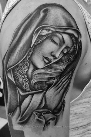 Get inked with a stunning Chicano style Mother Mary tattoo on your upper arm in London, GB. Symbolize faith and love with this beautiful design.