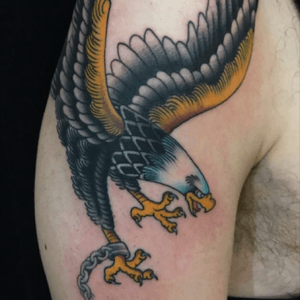 Get a stunning upper arm tattoo of an eagle in the illustrative traditional style by artist Eddy Ospina.