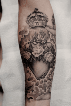 Stewart Robson's stunning design features a black and gray rose intertwined with a dagger, crowned by a sacred heart on the forearm.