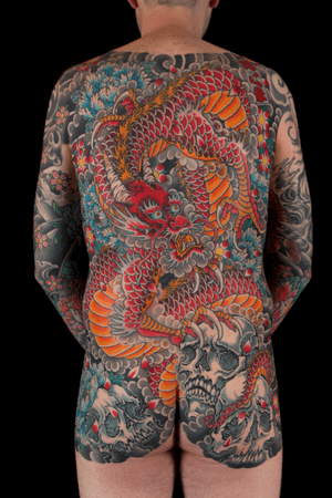 Intricate Japanese back piece tattoo featuring a dynamic dragon, delicate flower, and haunting skull by the talented artist Stewart Robson.