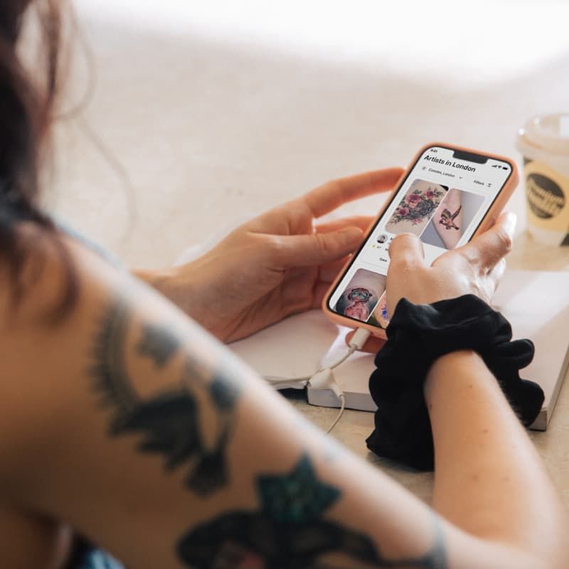 Tattooed woman looking down at her mobile phone in a bright modern office -  Free Photo (E47kA4) - Noun Project