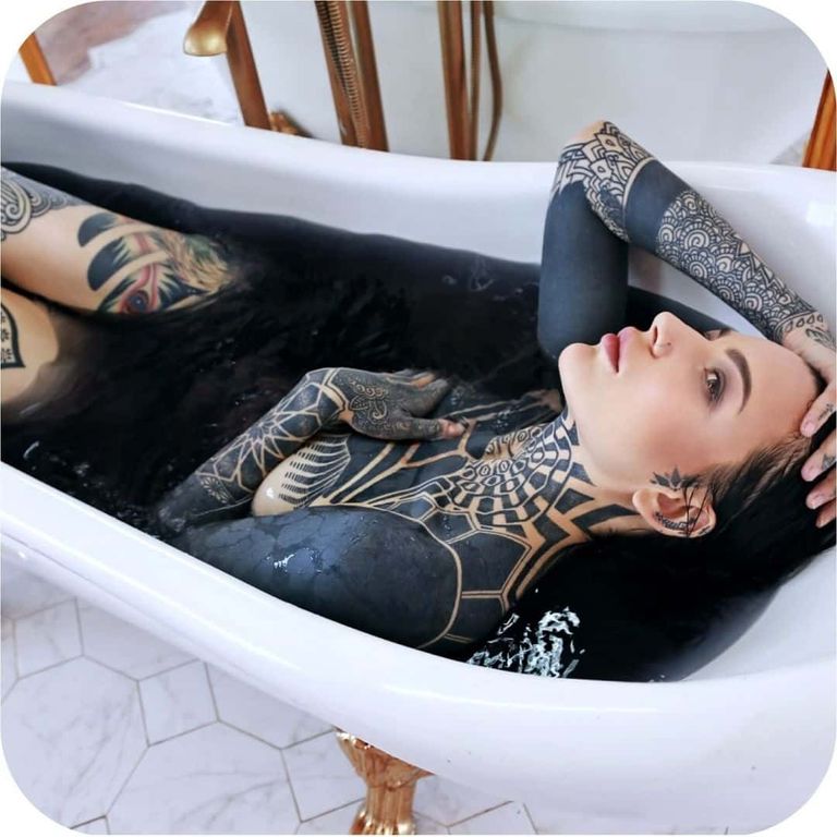 A blackwork bodysuit with ornamental patterns, in a full bath.