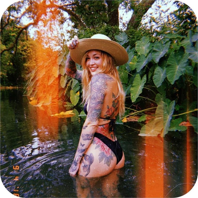 Floral tattoos across the back, arm and hip, in a river.